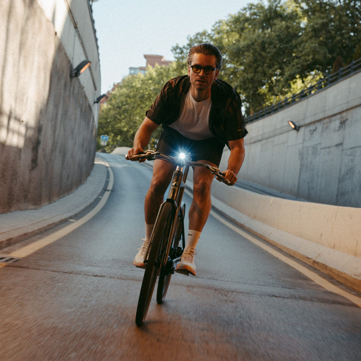 Mann fährt Desiknio-Bike mit eingeschaltetem Frontlicht durch Tunnel.